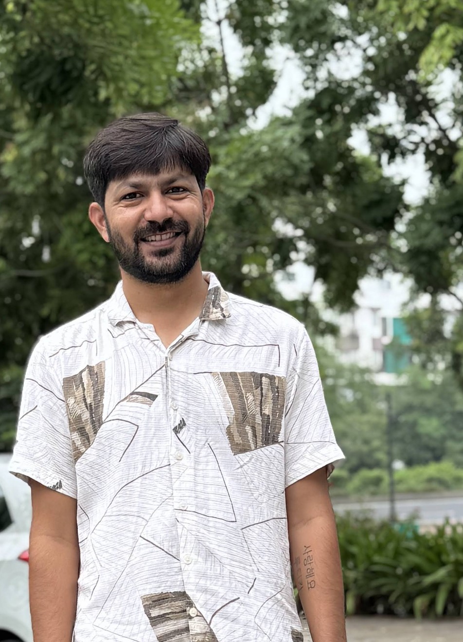 Mayur smiling outdoors in a patterned shirt